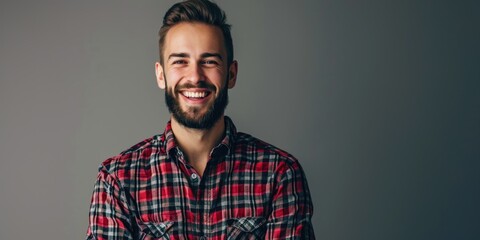 Obraz premium Friendly Young Man Smiling in a Red Plaid Shirt, Grey Background