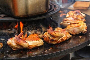 Roast frying grilled chicken on the barbecue outdoor. Tasty meat on open fire with smoke and flames. BBQ party on backyard. Family time concept. Rotisserie home cooking festival. Street food cafe
