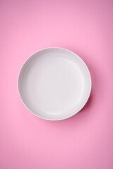 Empty round ceramic plate on a plain background, flatley with copy space