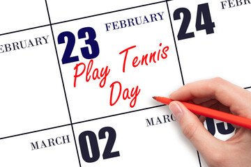 February 23. Hand writing text Play Tennis Day on calendar date. Save the date.