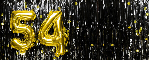 Gold foil balloon number number 54 on a background of black tinsel decoration. Birthday card,...