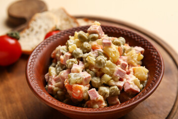 Bowl of tasty Olivier salad on yellow background, closeup