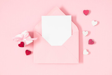 Creative minimal Valentines day concept. Envelope, valentines, hearts confetti on pastel pink background. Flat lay, top view, copy space