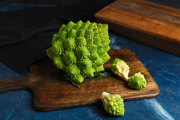Wooden board with romanesco cabbage on blue grunge table