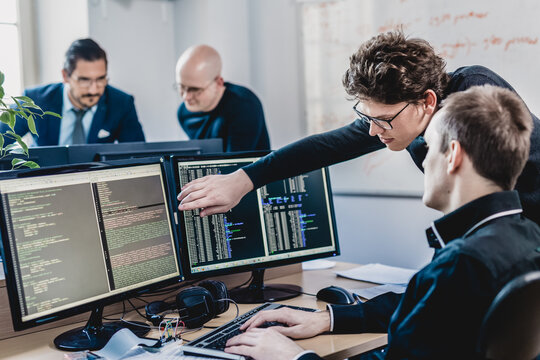 Startup business and entrepreneurship problem solving. Young AI programmers and IT software developers team brainstorming and programming on desktop computer in startup company share office space.