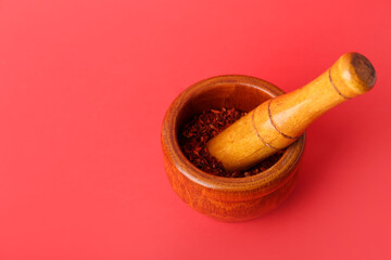 Wooden mortar and pestle with spices on red background