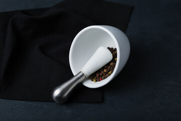 Mortar and pestle with peppercorns on dark background