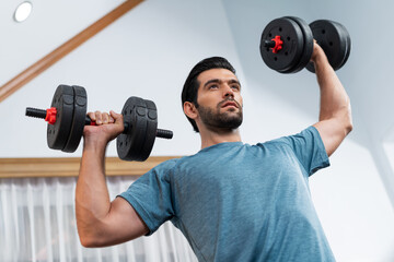 Athletic body and active sporty man lifting dumbbell weight for effective targeting muscle gain at gaiety home as concept of healthy fit body home workout lifestyle. - obrazy, fototapety, plakaty