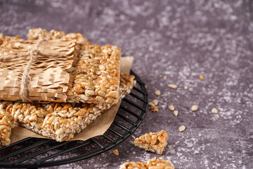 Stand with tasty kozinaki in parchment on grunge grey background