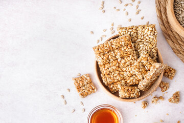 Bowls with tasty kozinaki, honey and sunflower seeds on white background