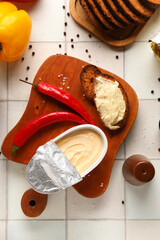 Wooden board with boxes of processed cheese, bread and vegetables on white tile background