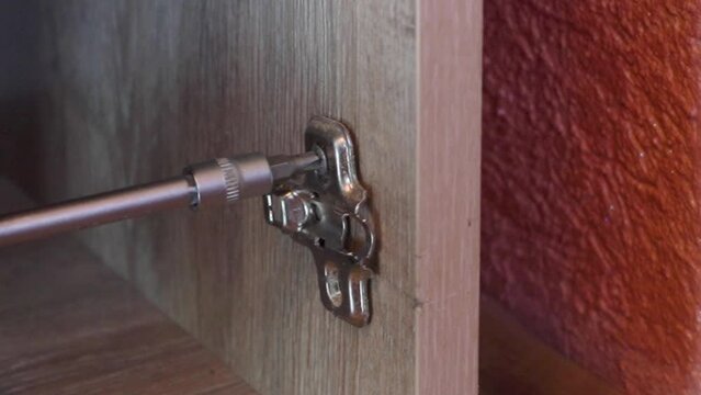 hinge furniture repair, replacing old broken hinges in furniture, unscrewing the screw that fastens the hinges to the door