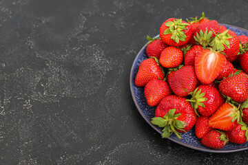 Plate with fresh strawberries on black background
