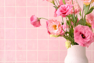 Vase with beautiful pink eustoma flowers on light tile background