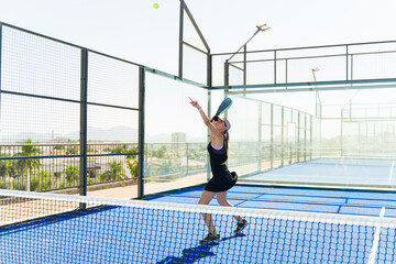 Fototapeta na wymiar Beautiful woman practicing her padel tennis serve