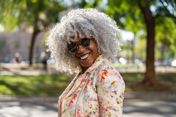 Stylish, smiling afro lady with grey afro hairstyle in sunny city