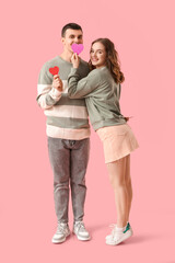 Funny young couple with paper hearts on pink background. Valentine's day celebration