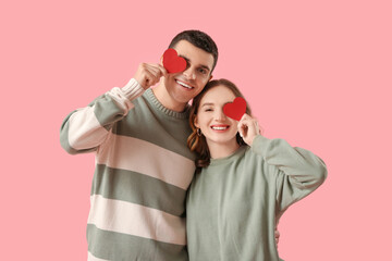 Funny young couple with paper hearts on pink background. Valentine's day celebration