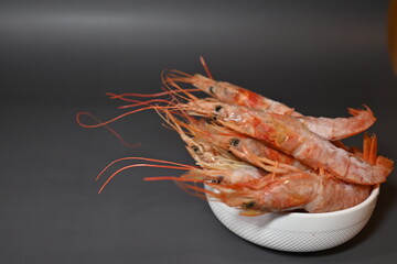 frozen pink queen shrimp in a bucket on a gray background
