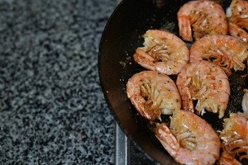 fried white-footed prawn hovstas close-up, browned cooked king prawns in a frying pan 