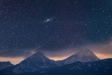 Beautiful night landscape. Snow covered mountains under beautiful bright Milky Way Galaxy.