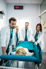 Nurses and doctors in a hurry taking patient to operation theatre. Patient on hospital bed pushed...