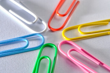Multi colored paper clips are folded in shape star white background.