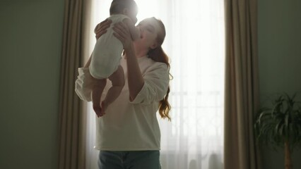 Mother picks up her newborn baby from the bed. Concept of Childhood, new Life, parenthood, maternity, motherhood. Happy mother picks up neonate toddler from bed. Cinematic advertisement for baby care