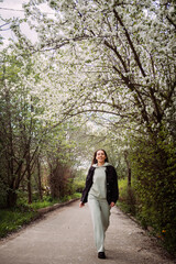 A woman standing under a tree. She appears to be dressed in outdoor clo