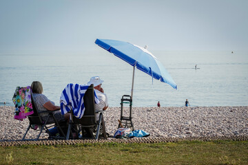 Man and wife enjoy the summer hot weather at Budleigh Salterton beach in East Devon, UK