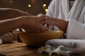 Obraz na płótnie Canvas Woman receiving hand treatment at wooden table in spa, closeup