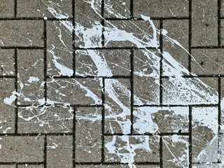 Paving stones from above with paint splatters and splatters of paint on them.