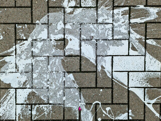Paving stones from above with paint splatters and splatters of paint on them.