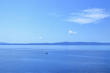 Blue Sea waves and mountains. Blue ocean background. Beautiful crystal clear sea water in Croatia. Beautiful landscape with turquoise water. Vacation and summer concept. Boat at sea
