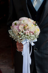 Detail of the groom with the bouquet of flowers waiting for the bride