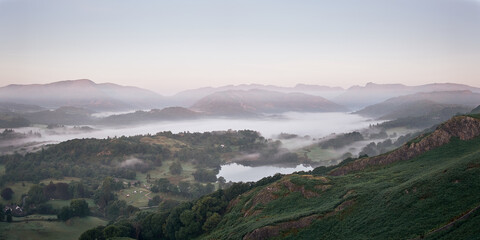 Panorama of a cloud inversion at dawn lies above Elterwater from Loughrigg. Loughrigg Tarn in the foreground, Crinkle Crags, Bowfell and the Landgale Pikes for the skyline, Lake District, UK