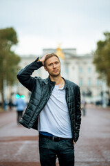 casual young man enjoying a serene moment at the majestic buckingham palace, a fusion of modern...