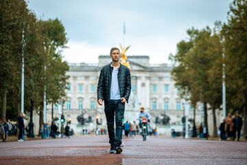 casual young man enjoying a serene moment at the majestic buckingham palace, a fusion of modern casual fashion and historical elegance in london's heart - obrazy, fototapety, plakaty