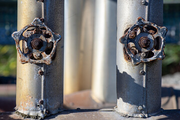 two old and rusty industrial liquid control faucets. One in each tube aligned parallel - obrazy, fototapety, plakaty