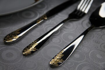 Gorgeous beautiful patterns on chrome-plated cutlery shimmering with light lying on a white...