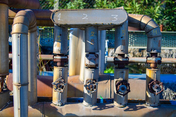 three old and rusty industrial liquid control faucets. One in each tube aligned parallel with...