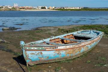 old artisanal wooden fishing boat in a phase of degradation on top of the mud at low tide of the...