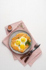 Fried eggs with cheese and sesame served on plate over napkin, vegetarian breakfast