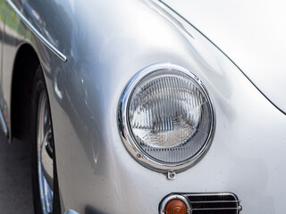 Classic retro car with close-up on headlights. Summer hot car parked on a beach. 
