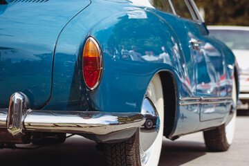 Classic retro car with close-up on headlights. Summer hot car parked on a beach. 