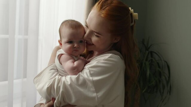Peaceful scene of caucasian newborn baby in mother's hands, calm innocence. With chubby cheeks, this little one is very picture of cuteness. Perfect for cinematic advertisement for baby care products