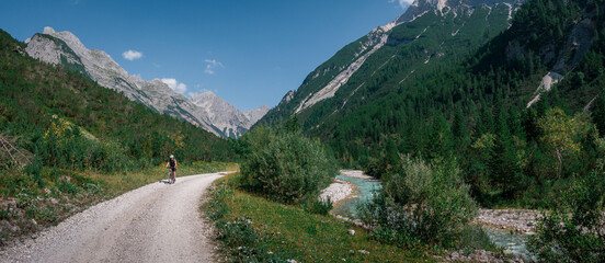 Man mountainbiking along the turquoise river Isar in the Karwendel mountains during sunny blue sky day in summer, Tyrol Austria. - 704096630