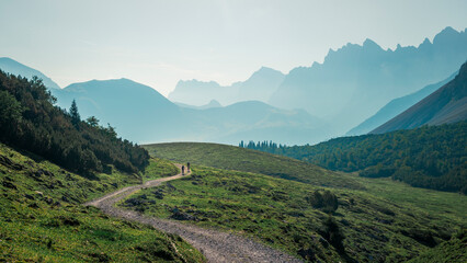 Mountainbiking along gravel road in the Karwendel mountains in front of blue mountain layers during...