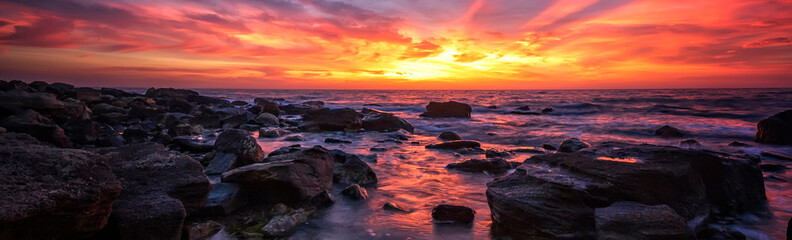 Amazing panoramic sunrise over the sea with rocks.
