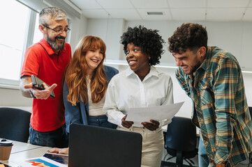 A happy interracial team is working on a project at office.